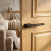 Hidden modern internal door handles in a bold matt black finish from the Lupina range, installed with a seamless hidden rosette on a natural oak door.