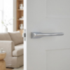 High-shine polished chrome hidden modern internal door handles from the Lupina collection, featuring a reflective mirror-like finish on a bright white door.