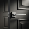 Salvia on Square Rosette timeless square door handles in a modern brushed chrome finish, installed on a sleek dark charcoal interior door.