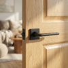 Setia on Square Rosette classic square internal door handles in a bold matt black finish, mounted on a natural oak door for a striking modern look.