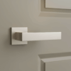 A greige door with a satin nickel Pina on Square Rosette handle, cozy yet modern feel, gentle lighting from the side