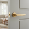 Elegant internal door handles showcasing the Alora lever on a round rosette in a matt gold finish, installed on a softly painted interior door.