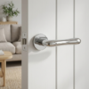 Cynia on Round Rosette in polished chrome, luxury lever internal door handles styled on a white panel door in a modern living space.