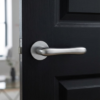 Cynia on Round Rosette in satin chrome, luxury lever internal door handles installed on a dark interior door.