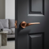 PVD copper Dalia on Round Rosette, adding warm metallic style with contemporary designer internal door handles on a dark door.