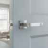 Bold internal door handles in polished chrome, featuring the Erica lever on a square rosette fitted to a pale blue internal door in a modern living space.