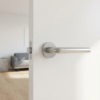 Elegant round internal door handle in satin chrome Funkia design on a white door within a bright minimalist living area.