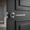 Hiacynta on Round Rosette in polished chrome, highlighting retro-style internal door handles on a dark grey panelled door.