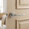 Hiacynta on Round Rosette in satin chrome, displaying retro-style internal door handles on a light oak panel door.