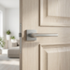 Minimalist square internal door handles in satin chrome, featuring the Jasmina lever on a square rosette mounted on a light wood internal door in a bright, modern interior.