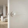 Matt white Kalmia on Round Rosette fitted to a light timber door, emphasising the sleek round internal door handle aesthetic in a soft, modern room.