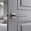 Titanium Kalmia on Round Rosette fitted to a grey panelled door, emphasising the sleek round internal door handle look in a stylish, modern living space.