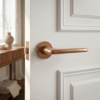 Lira on Round Rosette in PVD copper, offering luxury round internal door handles on a white paneled door.