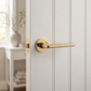 Lira on Round Rosette in polished gold, presenting luxury round internal door handles on a white cottage-style door.