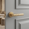 Lobelia on Round Rosette in matt gold, featuring modern round internal door handles on a soft grey panelled door.