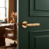 Lobelia on Round Rosette in polished gold, highlighting modern round internal door handles on a deep green interior door.