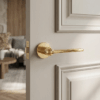 Lorenza on Round Rosette refined internal door handle in a luxurious polished gold finish, fitted to a light panelled door in an elegant interior.