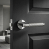 Molinia on Round Rosette polished chrome handle on a dark wood door, reflecting the clean style of understated round door handles.
