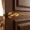 Petunia on Round Rosette in polished gold, highlighting sculpted round door handles on a classic dark wood panel door.