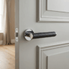 Egeria on Round Rosette in polished chrome with black leather grip, highlighting premium internal door handles on a grey panel door.