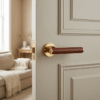 Egeria on Round Rosette in polished gold with brown leather grip, presenting premium internal door handles on a classic panelled door.