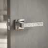 Amarylia on Square Rosette in polished chrome, featuring modern designer door handles with a textured lever on a grey interior door.
