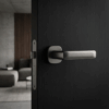 Stella on Rounded Square Rosette in matt black finish, showcasing modern round square door handles on a dark interior door